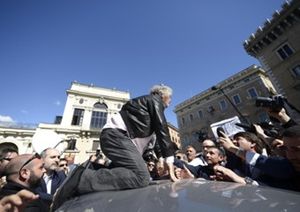 Beppe Grillo sale sul tetto di un auto per farsi vedere dalla folla che lo sta attendendo in piazza SS. Apostoli, a Roma.