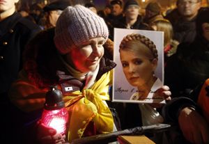 Una donna in strada a Kiev con una fotografia di Yulia Tymoshenko (Reuters).