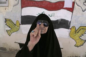 Una donna irachena mostra il dito tinto di viola dopo aver votato (Reuters).