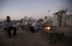 Il bivacco di una famiglia davanti ai resti della casa distrutta (Reuters).