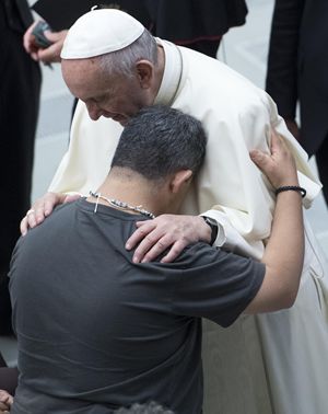 Papa Francesco abbraccia un fedele durante l'udienza generale