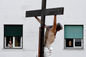 Gli abitanti del quartiere Arenella di Napoli seguono la Via Crucis celebrata dal parroco sul tetto della parrocchia (Ansa)