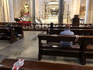 Un fedele in preghiera nella Basilica di San Nicola a Bari (Ansa)