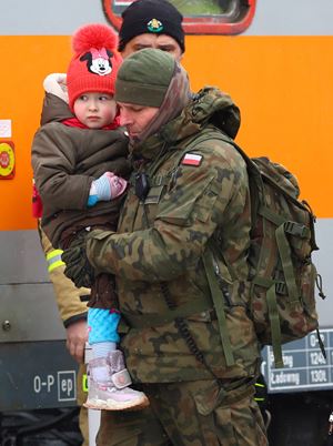 Un soldato polacco, al confine con l'Ucraina, aiuta un bambino a salire a bordo di un treno per Cracovia,