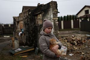 Una bimba accarezza un gatto davanti alle case distrutte di Moshchun, un villaggio ucraino non distante da Kviv. La foto, del 9 novembre scorso, è dell'agenzia Reuters. In alto e in copertina: dolore e bombe a Kharkiv. Foto Reuters.  