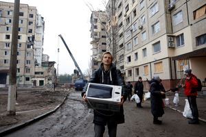 Denys scappa con un forno a microonde a Dnipro (Ucraina) il 18 gennaio 2023 dopo un bombardamento russo, con missili. Foto Reuters. 