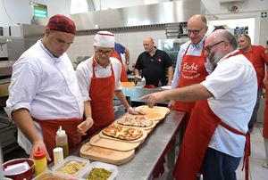 Nico Acampora in una delle sedi di PizzAut (a destra), progetto di pizzerie inclusive che danno lavoro e dignità ai ragazzi che soffrono di autismo, di fianco a Enrico Letta e ad alcuni pizzaioli. 