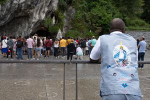 Pellegrini in preghiera davanti alla Grotta delle apparizioni di Lourdes (Ansa)